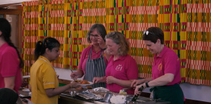 Volunteers serve up the different parts of lunch onto the plates for other volunteers to fill and deliver to guests.